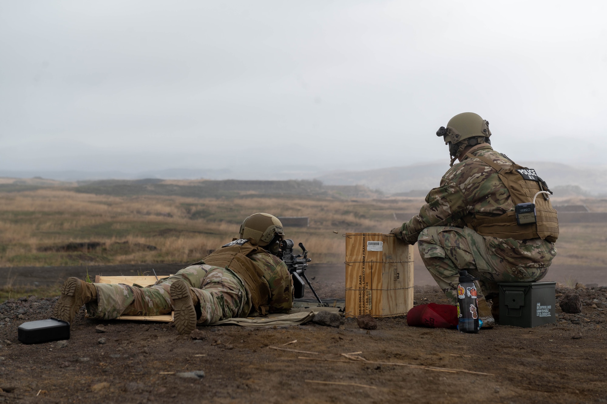 A service member runs through a target practice drill with guidance from another service member during an M249 Squad Automatic Weapon sustainment firing.