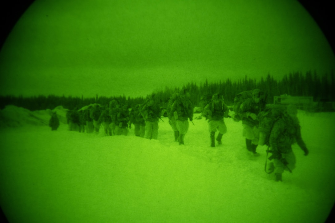 A line of soldiers walk through heavy snow.