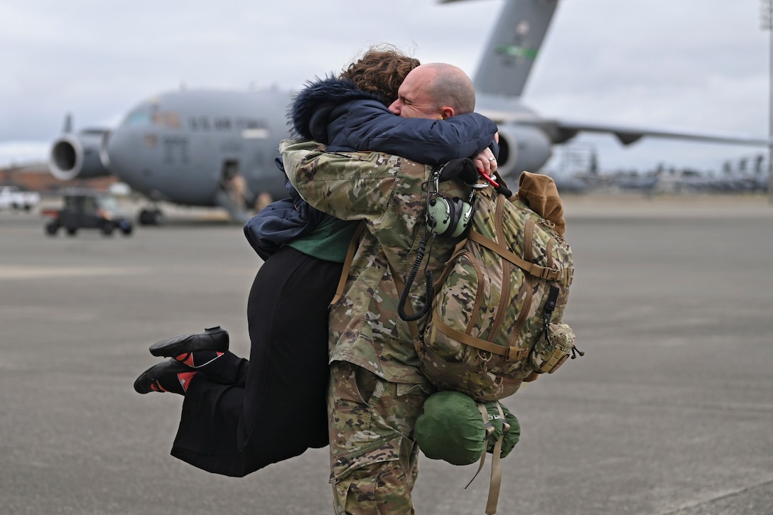 An airman gets a jump hug as he stands on the tarmac.