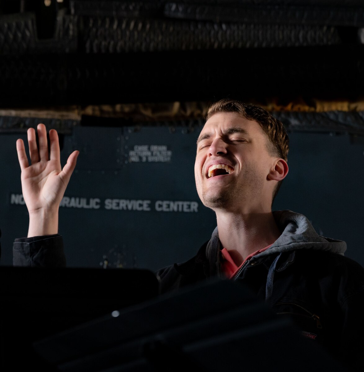 Airman 1st Class Jackson Heinze, 436th Airlift Wing religious affairs airman, sings a hymn during a religious service aboard a C-5M Super Galaxy at Dover Air Force Base, Delaware, April 9, 2023. For the first time since the COVID-19 pandemic, the 436th AW Chapel team hosted 130 Team Dover members aboard a C-5 for a religious service. (U.S. Air Force photo by Airman 1st Class Amanda Jett)