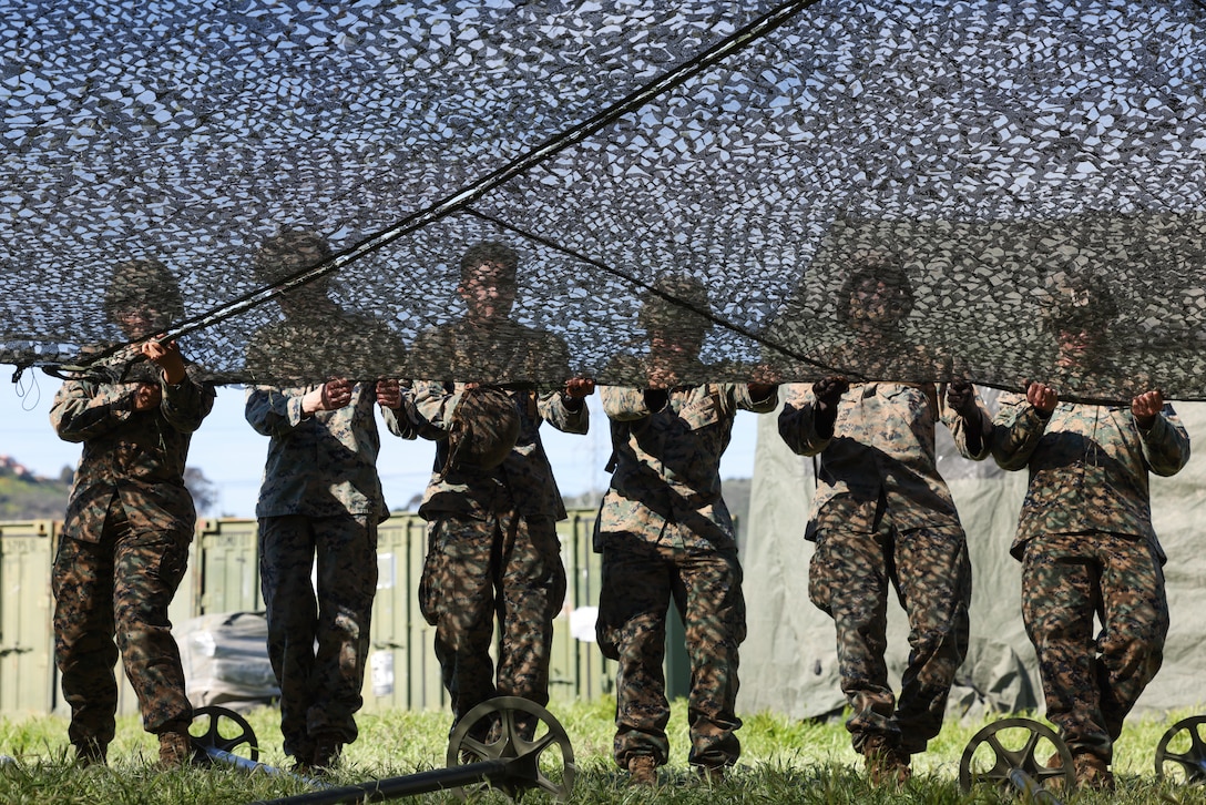 U.S. Marines with I Marine Expeditionary Force Information Group pull camouflage netting over a tent during a mini exercise on Marine Corps Base Camp Pendleton, California, Feb. 10, 2023. The mini exercise was conducted to familiarize Marines with equipment, tactical convoy training and battalion tactical standard operating procedures in preparation for Exercise Balikatan 2023. (U.S. Marine Corps photo by Sgt. Anabel Abreu Rodriguez)