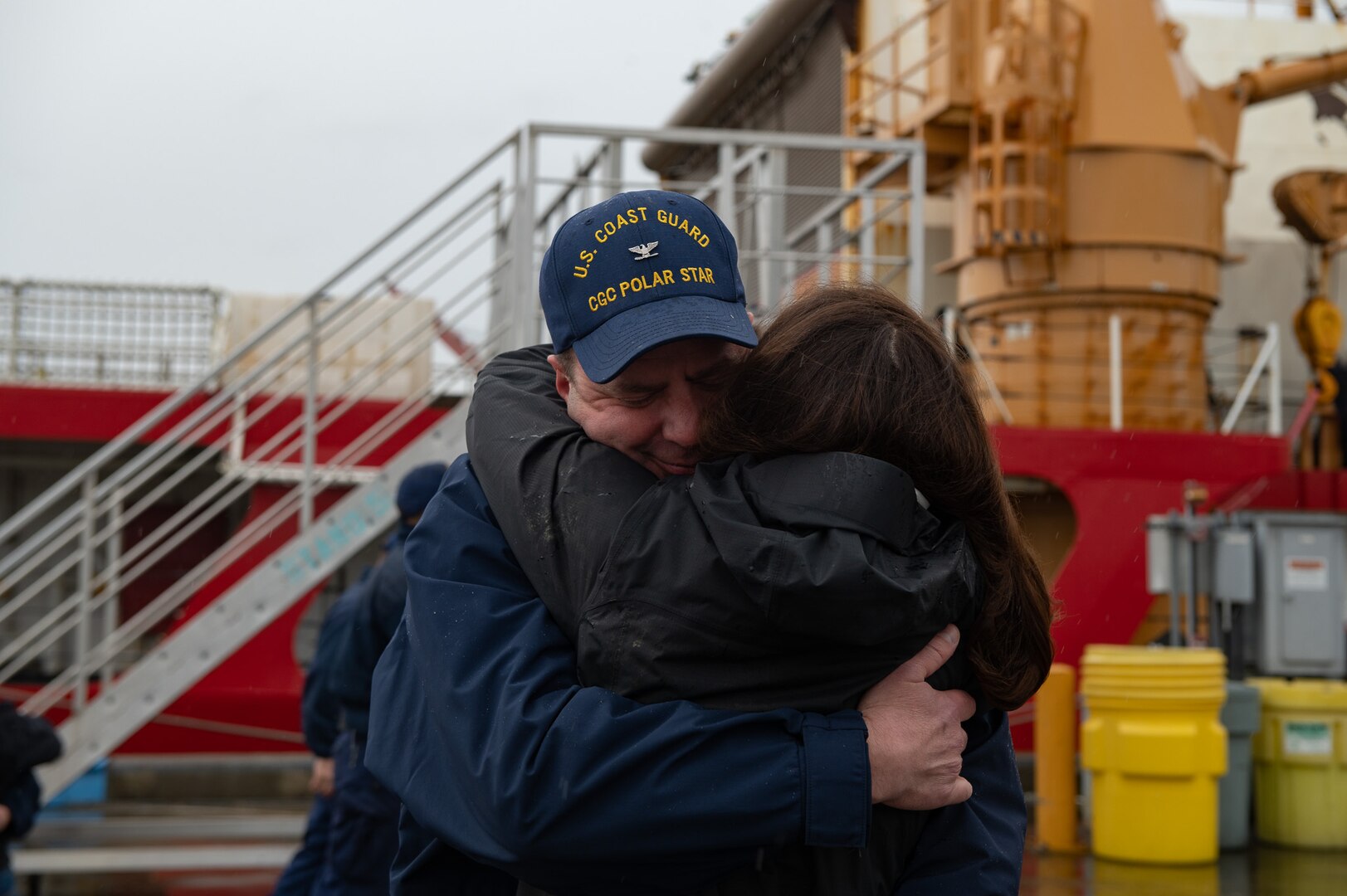 USCGC Polar Star (WAGB 10) family members hold sign waiting for the arrival of thier Coast Guardsman, April 8, 2022 in Seattle, Washington. Polar Star returned after completing Operation Deep Freeze 2022. (U.S. Coast Guard photo by Petty Officer 3rd Class Diolanda Caballero)