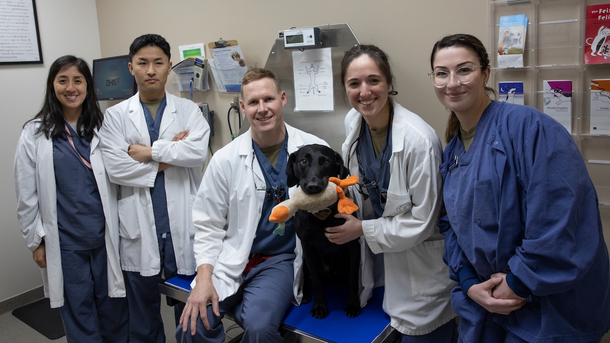 Five people posing for group photo with dog