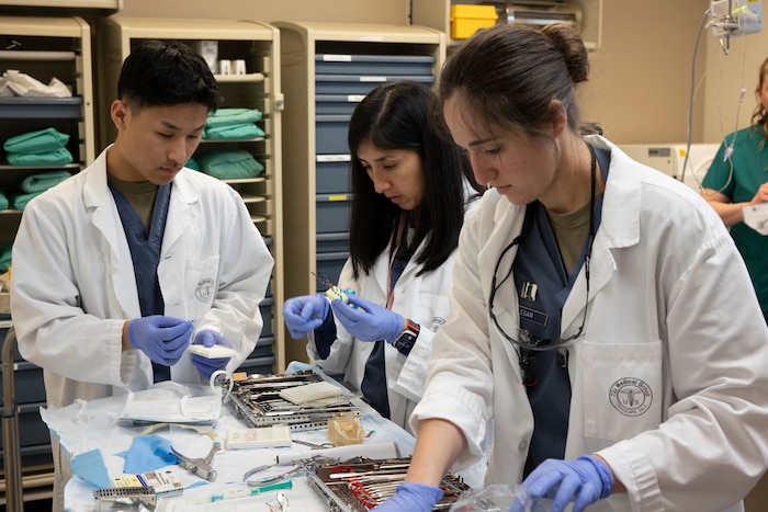 Three people preparing dental equipment