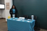 Woman stands at table with information about sexual assualt awareness and prevention.