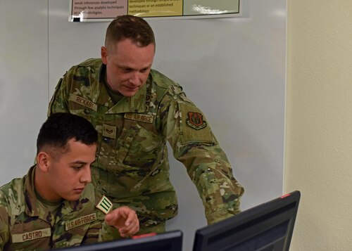 U.S. Air Force Staff Sgt. Dylan Rickaby, 315th Training Squadron instructor, assists Airman Brian Castro, 315th TRS student, at Goodfellow Air Force Base, Texas, April 7, 2023. Geospatial intelligence analysts provide imagery support to other intel specialties. (U.S. Air Force photo by Senior Airman Sarah Williams)