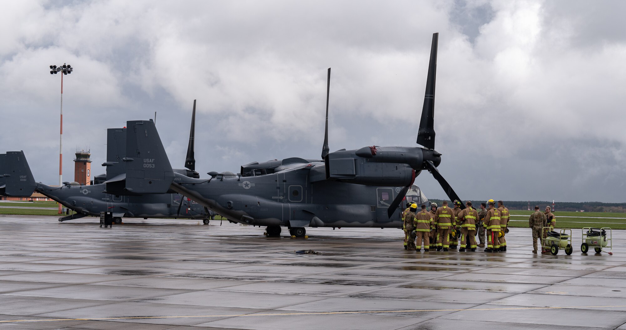 Personnel assigned to the 100th Air Refueling Wing and 352nd Special Operations Wing, stand on the flightline by a 352nd SOW CV-22B Osprey aircraft, after extinguishing a simulated fire, March 31, 2023, at Royal Air Force Mildenhall, England.