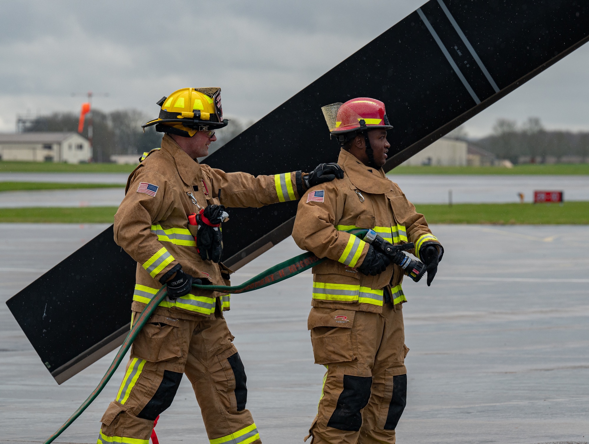 U.S. Air Force Staff Sgt. Justin Sigler, right, and Daniel Hodkinson, left, 100th Civil Engineering Squadron fire fighters, practice approaching and extinguishing a simulated fire of a CV-22B Osprey aircraft assigned to the 352nd Special Operations Wing, March 31, 2023, at Royal Air Force Mildenhall, England.
