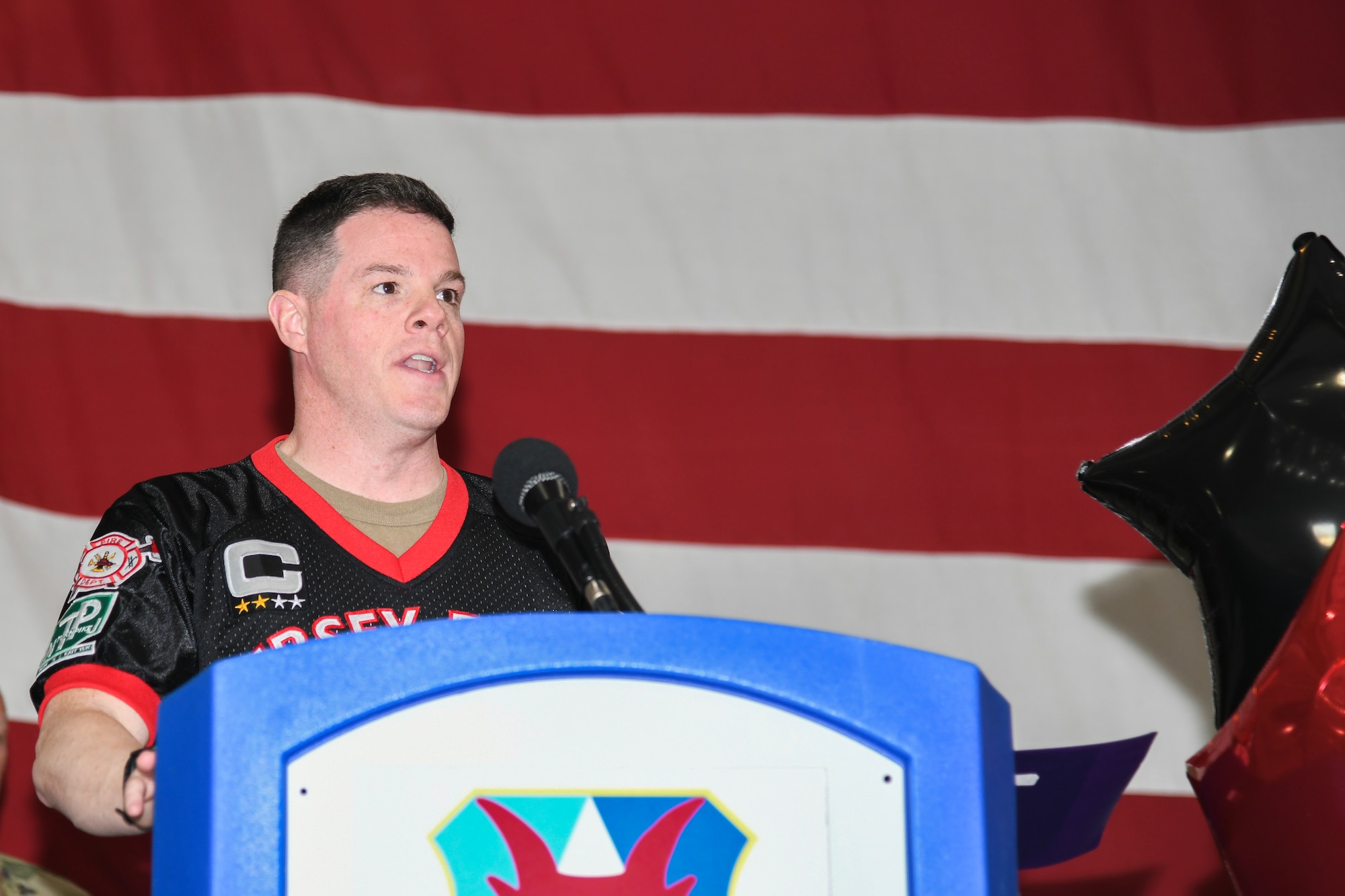 A photo of Lt. Col. Brian Cooper, 177th Maintenance Group commander, speaks at a podium.