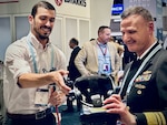 Naval Surface Warfare Center, Carderock Division engineer Dr. Lee Huntington briefs Vice Adm. William Galinis, Commander, Naval Sea Systems Command, on Carderock’s virtual paint sprayer during the 2023 Sea-Air-Space Exposition at the Gaylord Convention Center in National Harbor, Md., on April 4. (U.S. Navy photo by Monica McCoy)