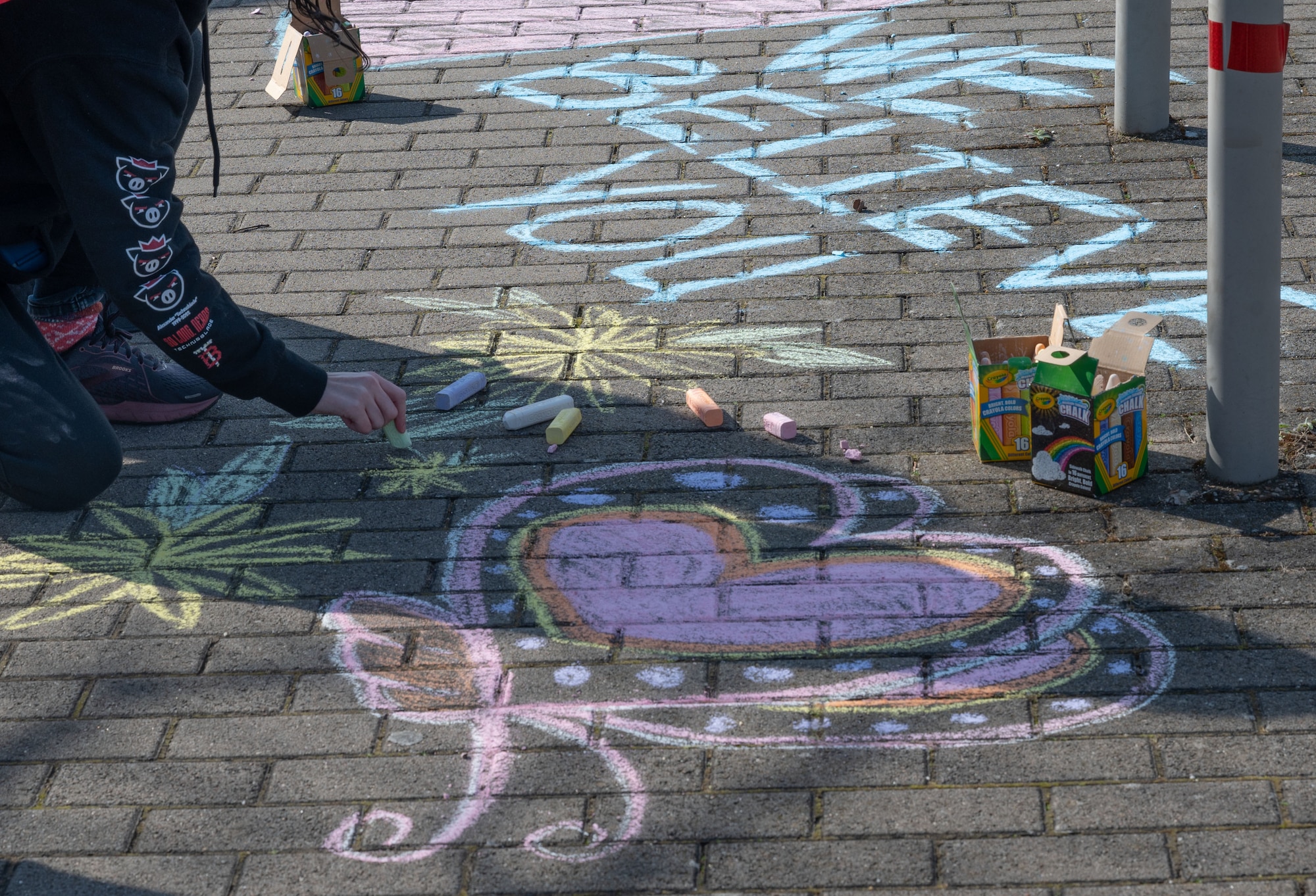 Volunteers decorate the entrance point of a Volksmarch event, a sexual assault awareness walk and fair, at Ramstein Air Base, Germany, April 6, 2023. The artwork colored the ground and had words of affirmation and inspiration. (U.S. Air Force photo by Senior Airman Andrew Bertain)