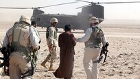 Historical image of CID Agents leading suspect to a CH-47 helicopter in Afghanistan
