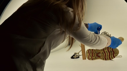 Forensic Scientist examining and taking pictures of footwear evidence in a light box, in the lab