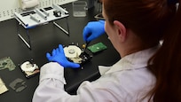 Forensic Scientist disassembling evidence, a computer hard drive, in the lab