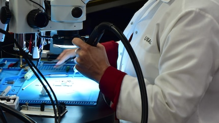Forensic Scientist examining electronic evidence using a microscope in the lab