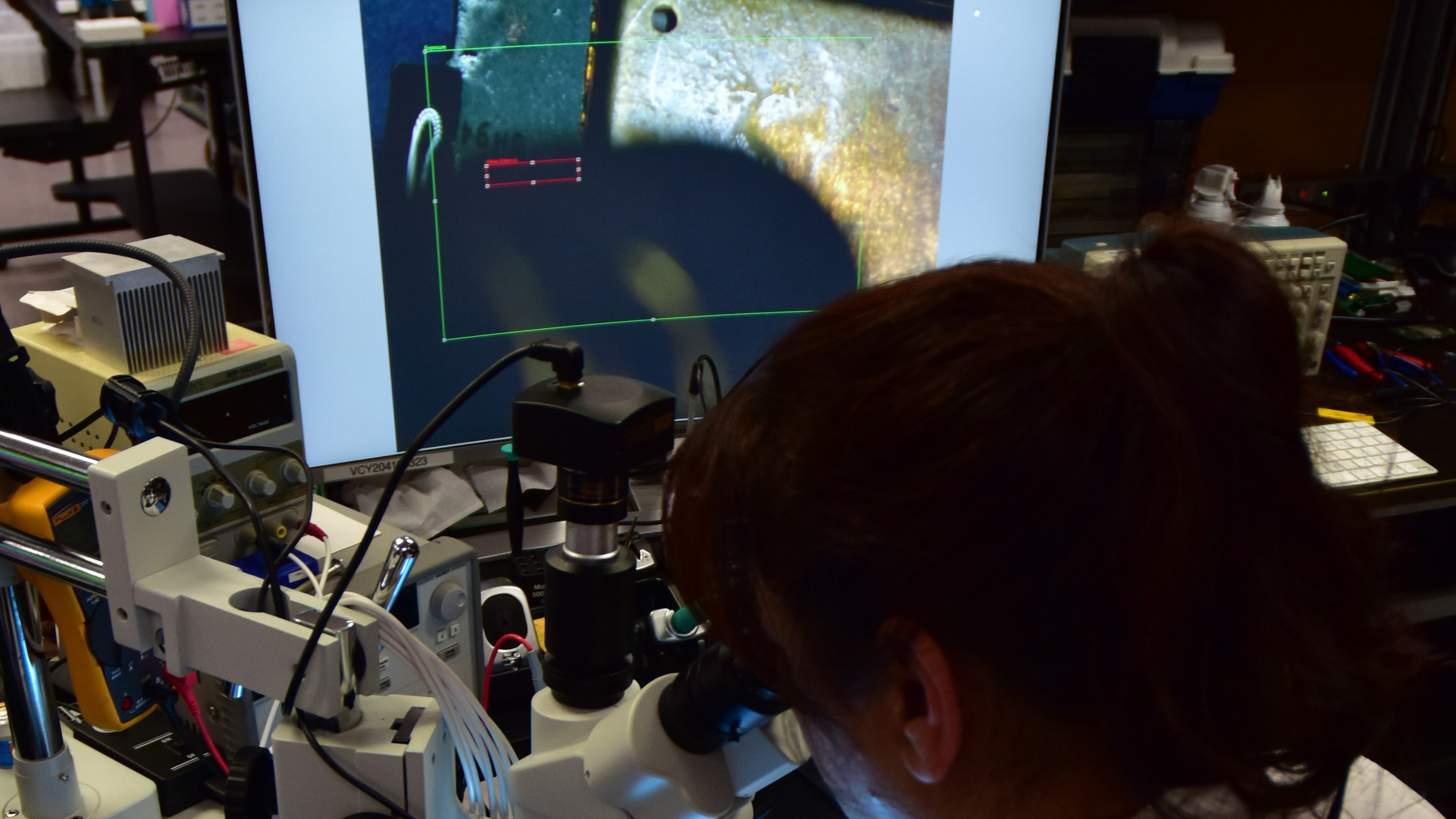 Forensic Scientist examining evidence under a microscope in the lab