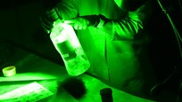 Forensic Scientist examining fingerprints on a bottle in the lab