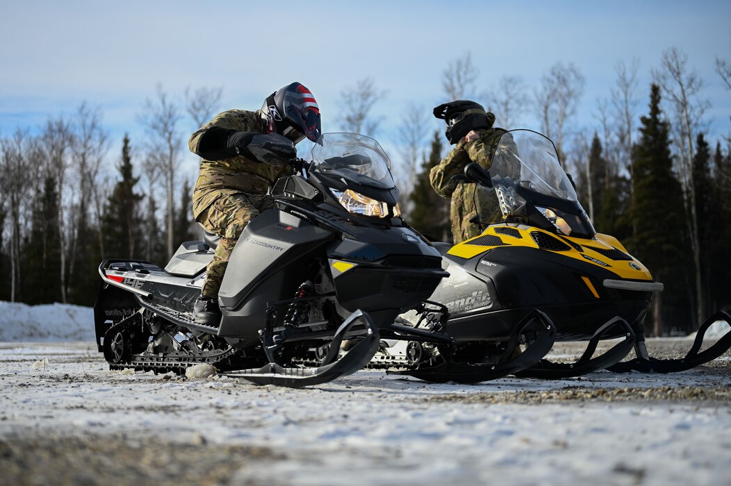 U.S. Air Force Staff Sgt. Stefan Sankovic, left, 3rd Air Support Operations Squadron vehicle fleet manager, and Staff Sgt. Clayton Rose, 3 ASOS power production craftsman, mount snowmobiles during an arctic training in Delta Junction, Alaska, March 22, 2023