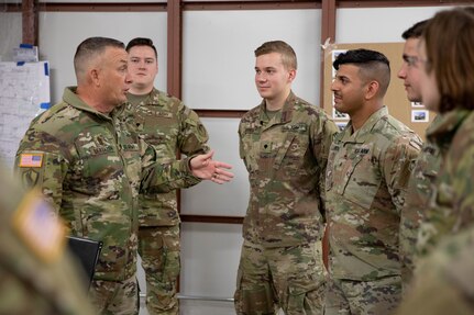 A group of Soldiers standing and having a conversation in a warehouse.