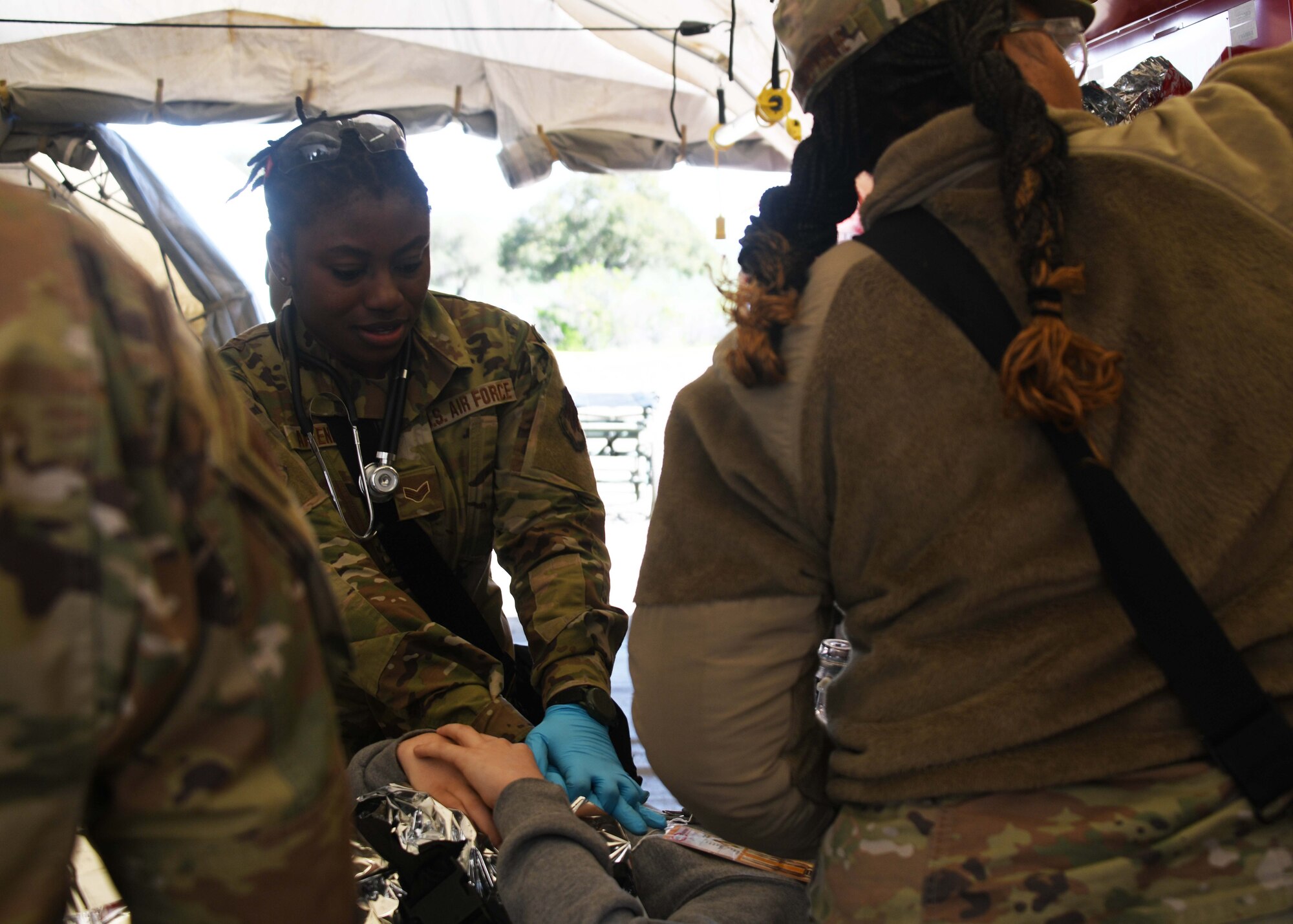 A military medic does simulates press compressions on an actor on a stretcher