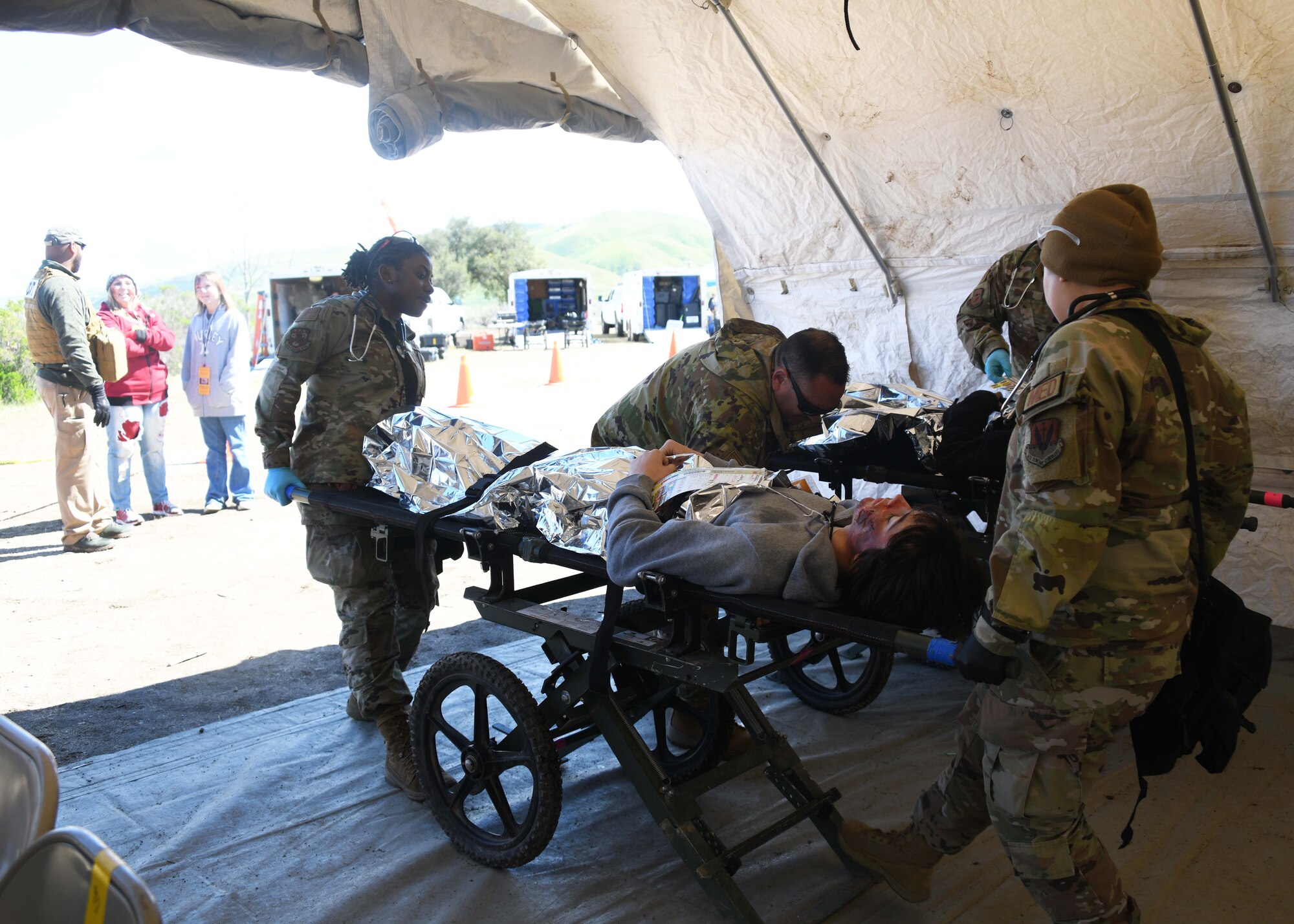 Two military medical personnel move an actor on a stretcher