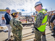 The Honorable Erik Raven, Under Secretary of the Navy, and Adm. Lisa Franchetti, Vice Chief of Naval Operations, discuss ongoing seismic mitigations at Dry Dock 4 at Puget Sound Naval Shipyard & Intermediate Maintenance Facility in Bremerton, Washington, March 29, 2023. Raven and Franchetti met with shipyard leadership during their visit to discuss infrastructure upgrades and work planned as part of the Shipyard Infrastructure Optimization Program, the Navy’s once-in-a-century investment to reconfigure, modernize and optimize its four aging public shipyards. (U.S Navy photo by Wendy Hallmark)
