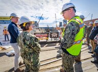 The Honorable Erik Raven, Under Secretary of the Navy, and Adm. Lisa Franchetti, Vice Chief of Naval Operations, discuss ongoing seismic mitigations at Dry Dock 4 at Puget Sound Naval Shipyard & Intermediate Maintenance Facility in Bremerton, Washington, March 29, 2023. Raven and Franchetti met with shipyard leadership during their visit to discuss infrastructure upgrades and work planned as part of the Shipyard Infrastructure Optimization Program, the Navy’s once-in-a-century investment to reconfigure, modernize and optimize its four aging public shipyards. (U.S Navy photo by Wendy Hallmark)