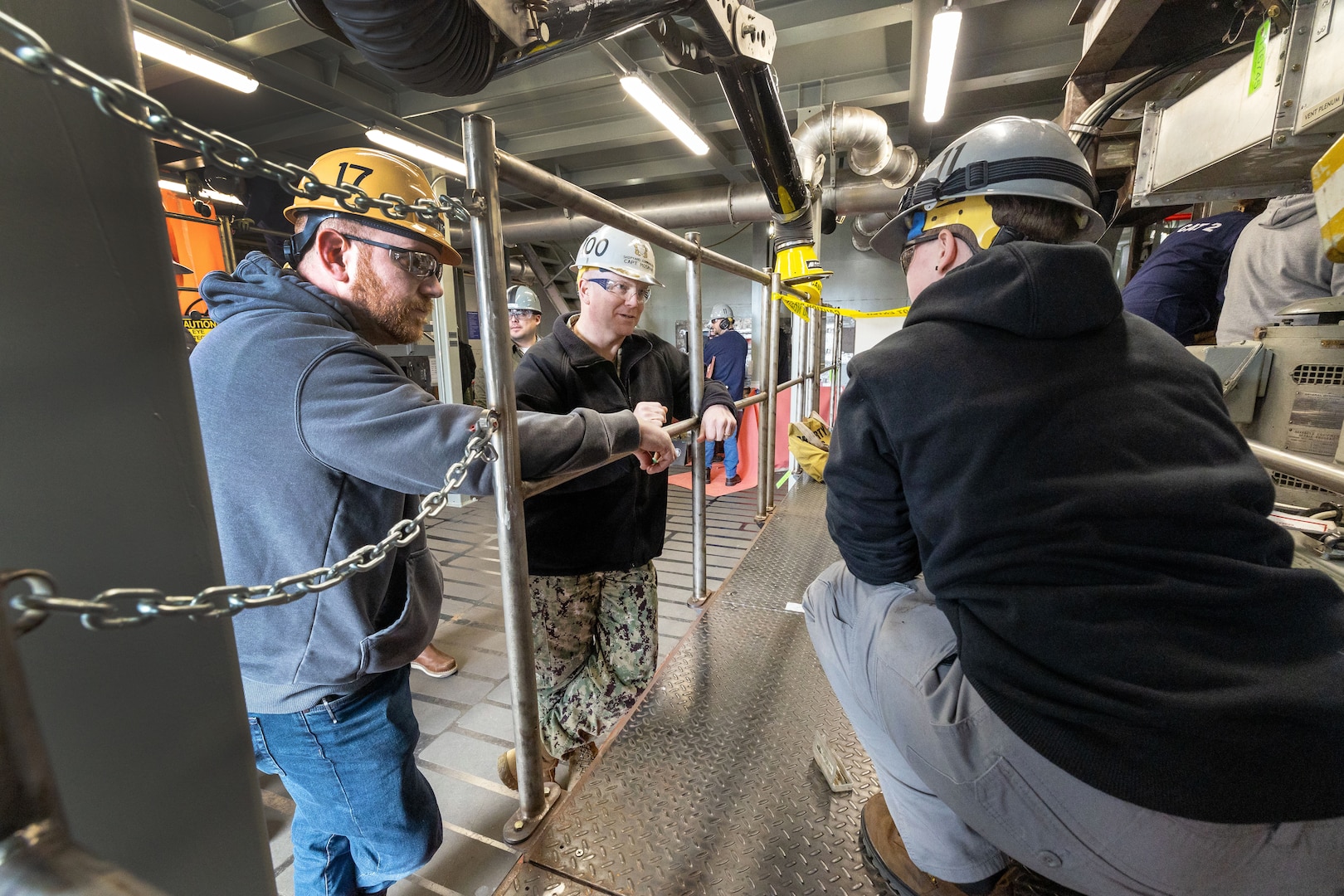 Capt. Jip Mosman, commander, Puget Sound Naval Shipyard & Intermediate Maintenance Facility, visits with trainees April 5, 2023, while touring a deck plate mock-up area in the newly re-dedicated Shop 11/17 School of Steel training facility with James Broshears, training instuctor, Shop 17, Sheet Metal, at PSNS & IMF in Bremerton, Washington.  (U.S. Navy photo by Wendy Hallmark)