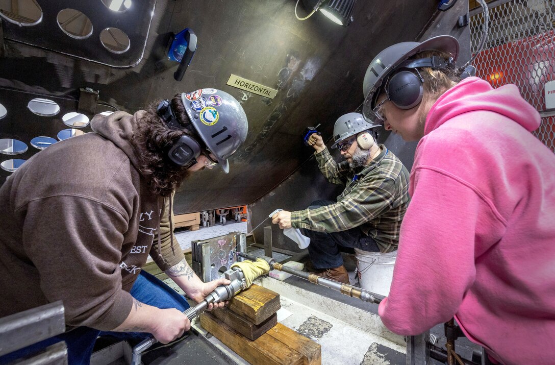 Shipfitters Glen Phillips and Brittany Schroeder, both Shop 11, Shipfitter, work with Joe Cantu, training instructor, Shop 11, Shipfitter, inside the School of Steel training area at Puget Sound Naval Shipyard & Intermediate Maintenance Facility in Bremerton, Washington. (U.S. Navy photo by Wendy Hallmark)