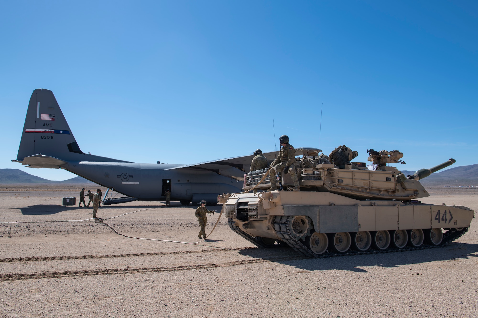 U.S. Army Soldiers from the 1st Armored Division and U.S. Air Force Airmen from the 317th Airlift Wing refuel an M1A2 Abrams tank from a C-130J Super Hercules during Operation Night King  in the California desert March 26, 2023.