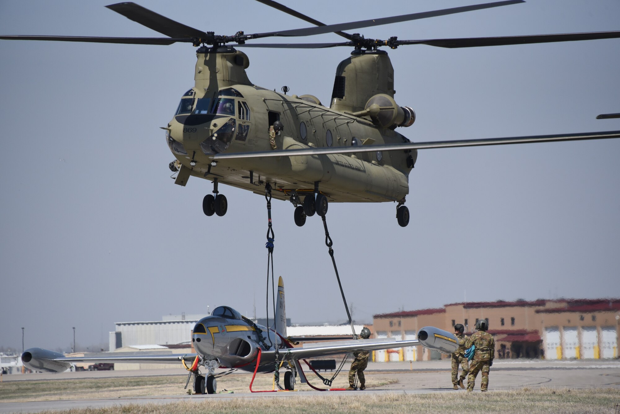 Iowa Army National Guard CH-47 Chinook helicopter picks up a F-80 fighter jet at the Air National Guard paint facility