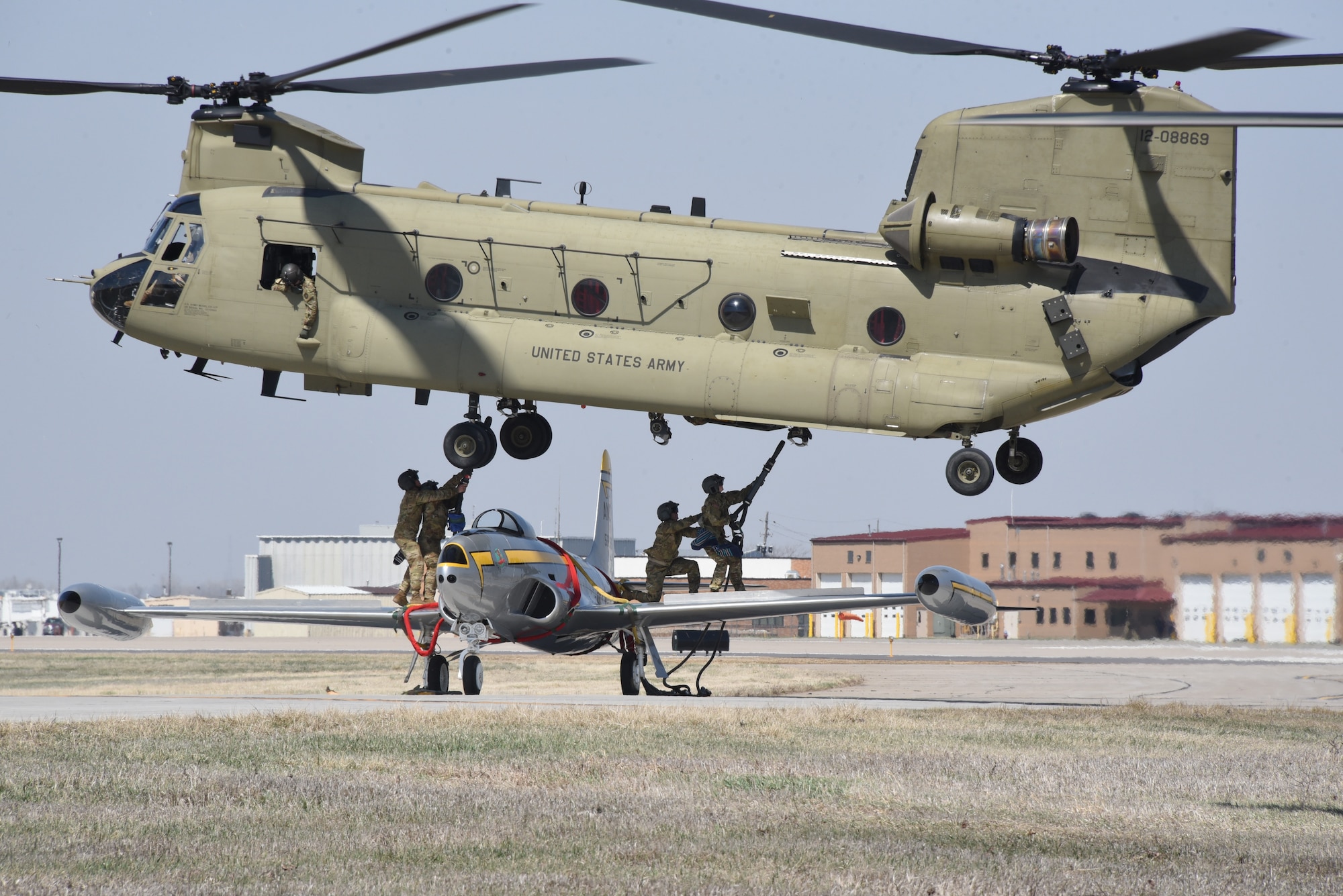 Iowa Army National Guard CH-47 Chinook helicopter picks up a F-80 fighter jet at the Air National Guard paint facility