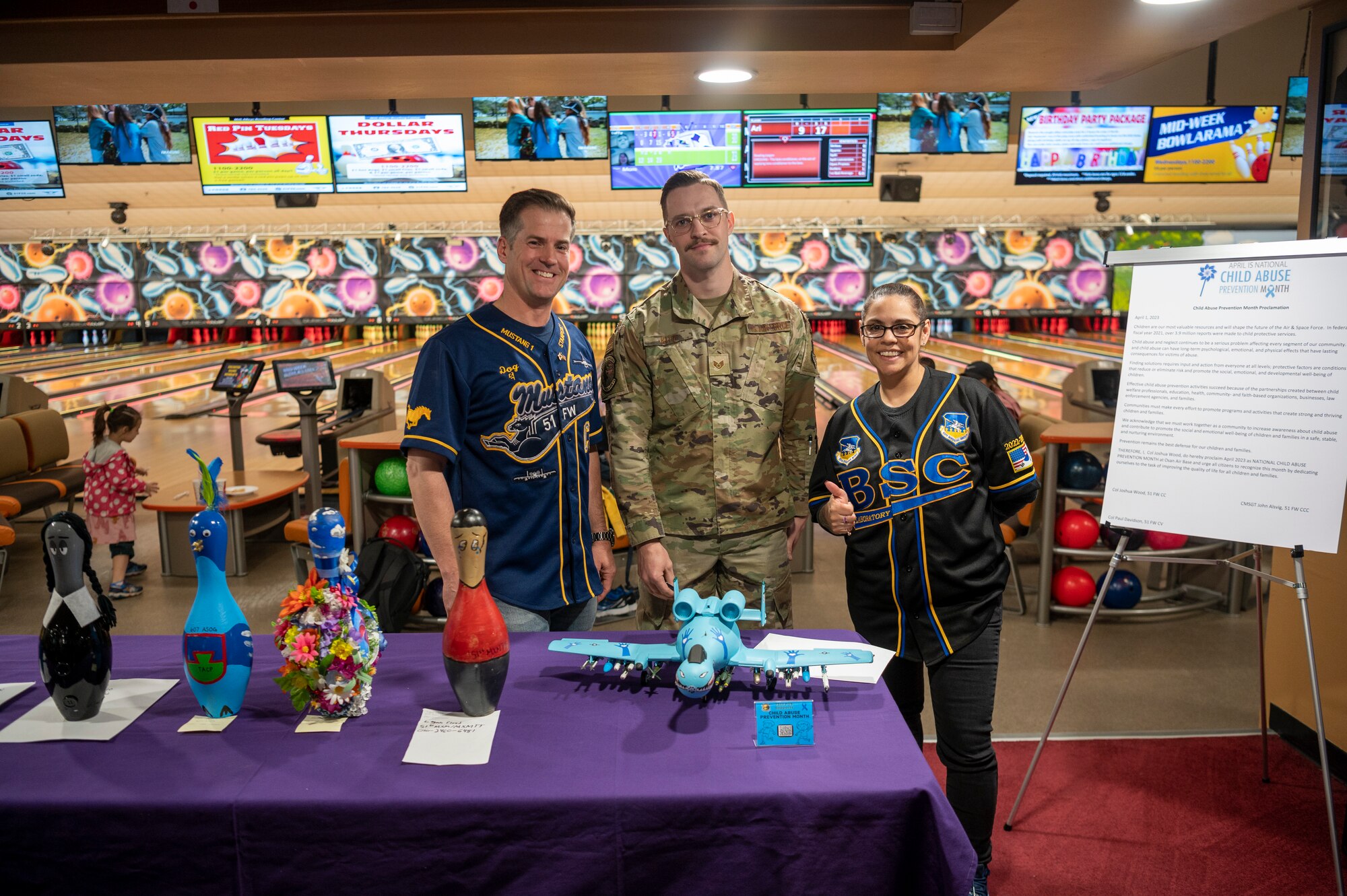 U.S. Air Force Col. Joshua Wood, 51st Fighter Wing commander, Chief Master Sgt. Lisa Thrasher-Stallard, 51st Medical Group command chief, and Senior Airman Andrew Kitz, 25th Fighter Generation Squadron crew chief, pose for a photo with Kitz’s winning pin for bowling pin decoration contest at Osan Air Base, Republic of Korea, April 7, 2023. The contest was held in observation of National Child Abuse Prevention Month. (U.S. Air Force photo by Airman 1st Class Aaron Edwards)
