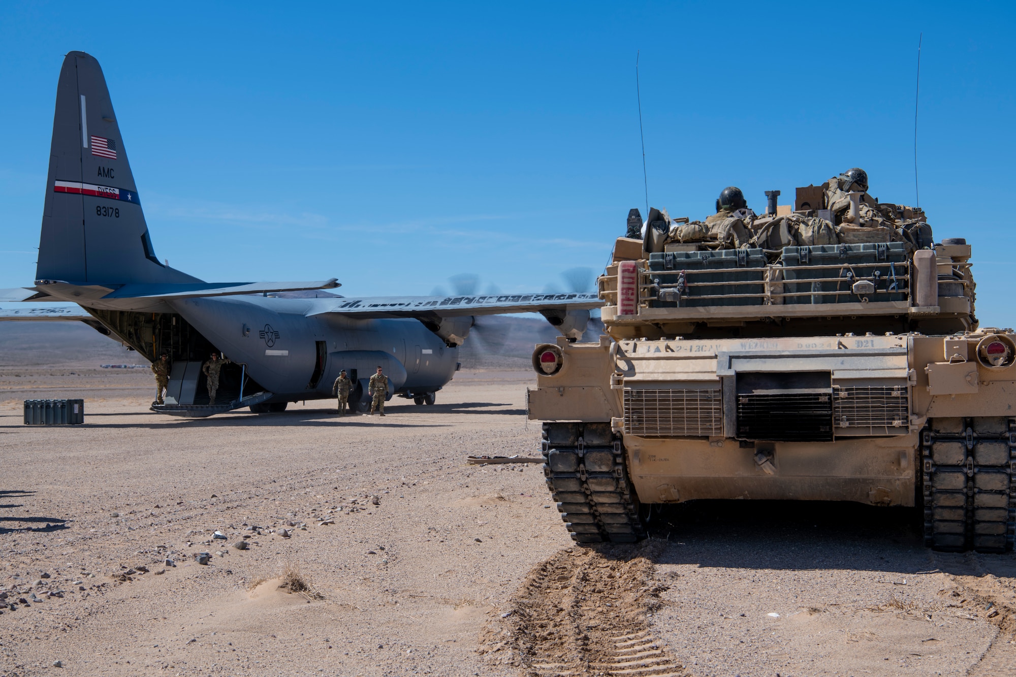 U.S. Army Soldiers from the 1st Armored Division park a M1A2 Abrams tank next to a C-130J Super Hercules in the California desert during Operation Night King March 26, 2023.