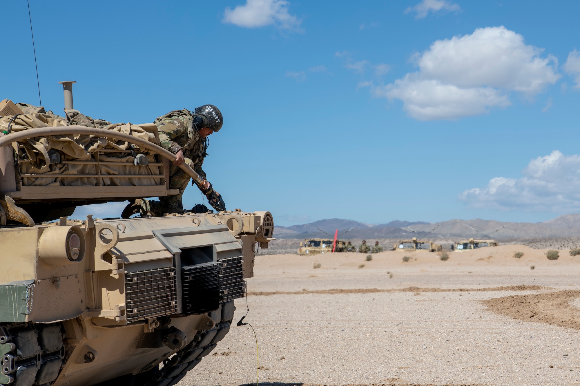 A U.S. Army Soldier from the 1st Armored Division refuels an M1A2 Abrams tank from a C-130J Super Hercules in the California desert during Operation Night King March 26, 2023.