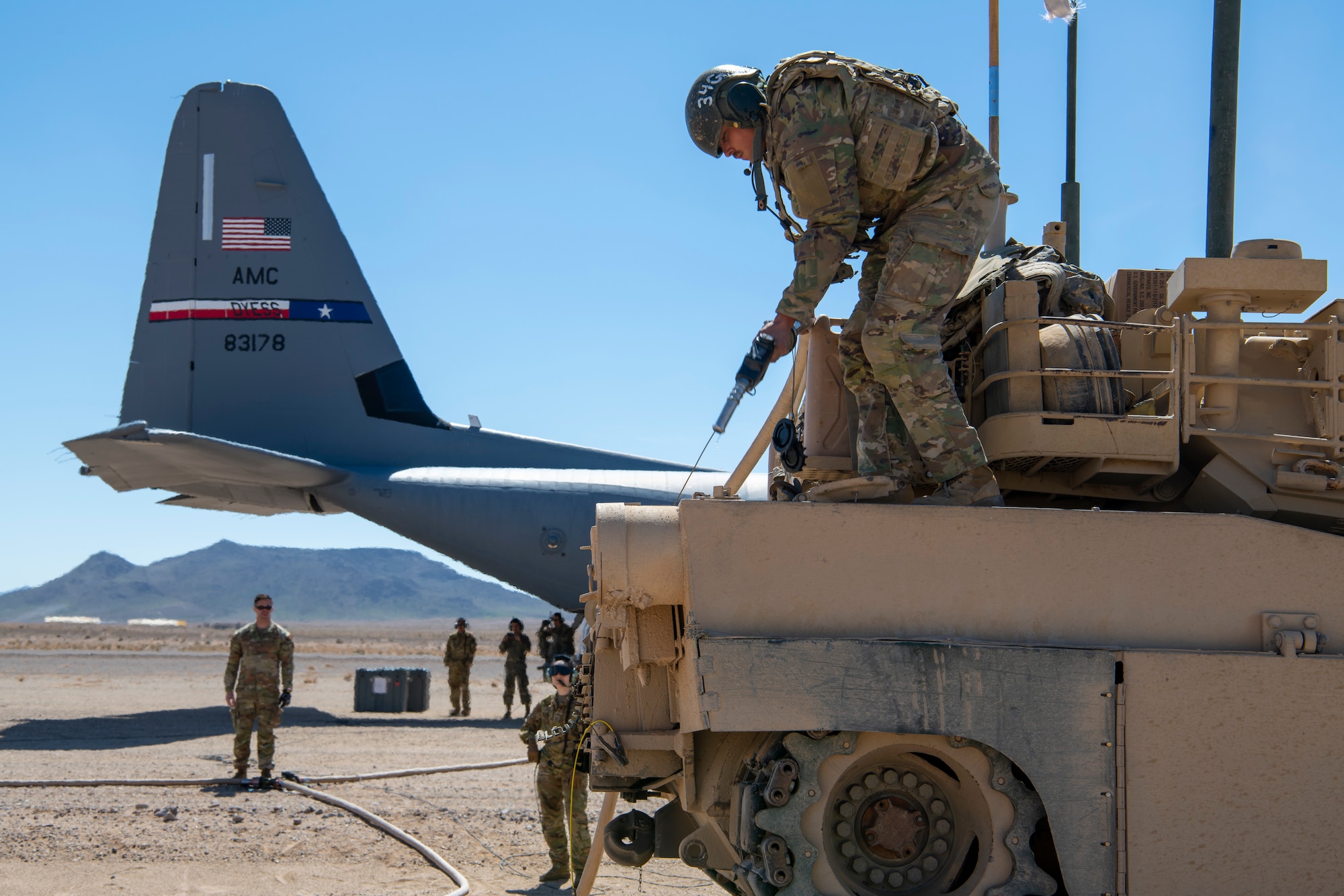 A U.S. Army Soldier from the 1st Armored Division refuels an M1A2 Abrams tank from a C-130J Super Hercules in the California desert March 26, 2023.