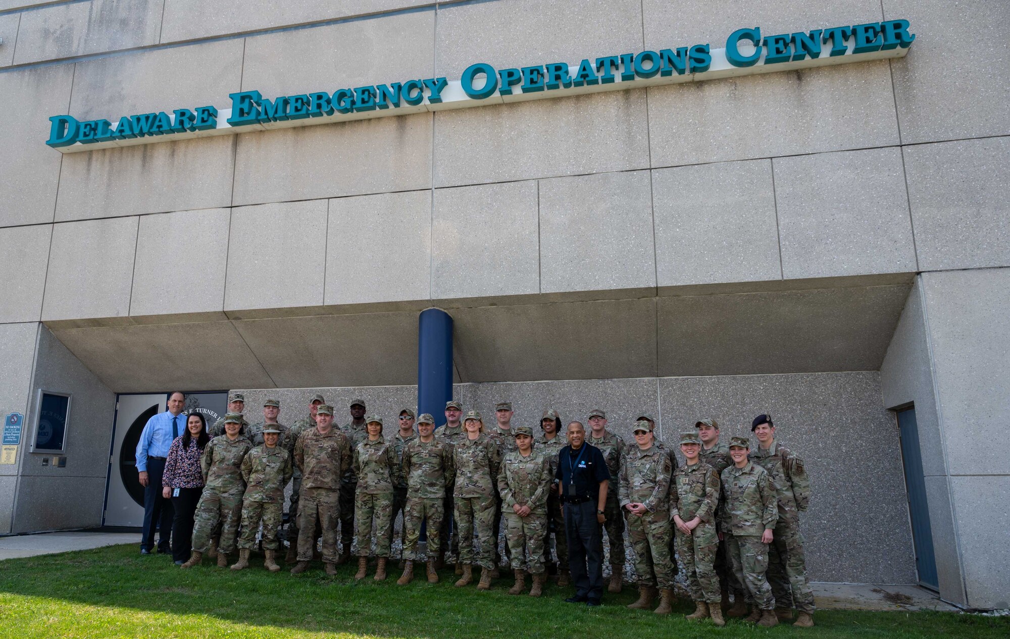Representatives from the 436th Mission Support Group and the 512th MSG pose for a photo in front of the Delaware Emergency Management Agency Emergency Operations Center in Smyrna, Delaware, April 6, 2023. During the immersion event, DEMA was able to share best practices with Team Dover Airmen regarding preparedness for natural disasters, terrorism response, emergency operations center training, behavior threat analysis for school safety and community engagement. (U.S. Air Force photo by Senior Airman Faith Barron)