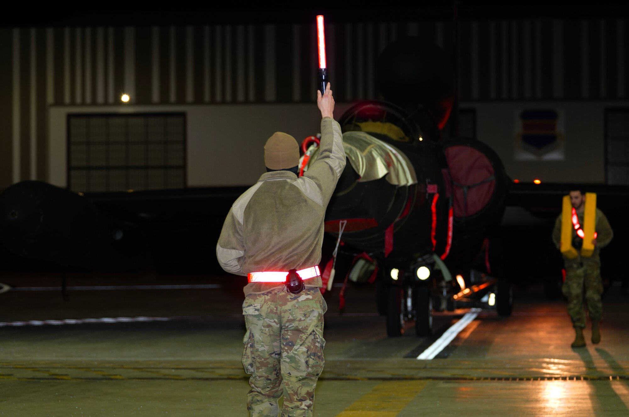 A U.S. Air Force 9th Aircraft Maintenance Squadron avionics specialist and 9th AMXS support technician guide a U-2 Dragon Lady into a hangar following an evening flight in support of Dragon Flag EAST, March 27, 2023, at Offutt Air Force Base, Nebraska.