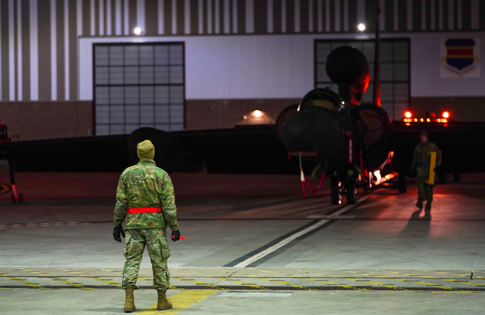 A U.S. Air Force 9th Aircraft Maintenance Squadron electrical and environmental systems craftsman guides a U-2 Dragon Lady into a hangar following an evening flight in support of Dragon Flag EAST, April 1, 2023, at Offutt Air Force Base, Nebraska.
