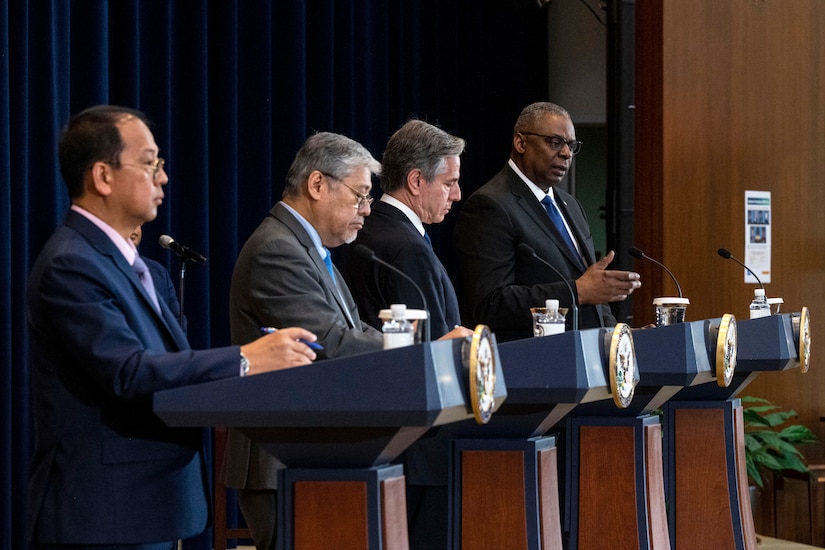 Four men stand on a stage behind podiums.