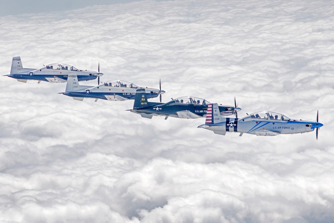 Four planes fly in formation above the clouds.