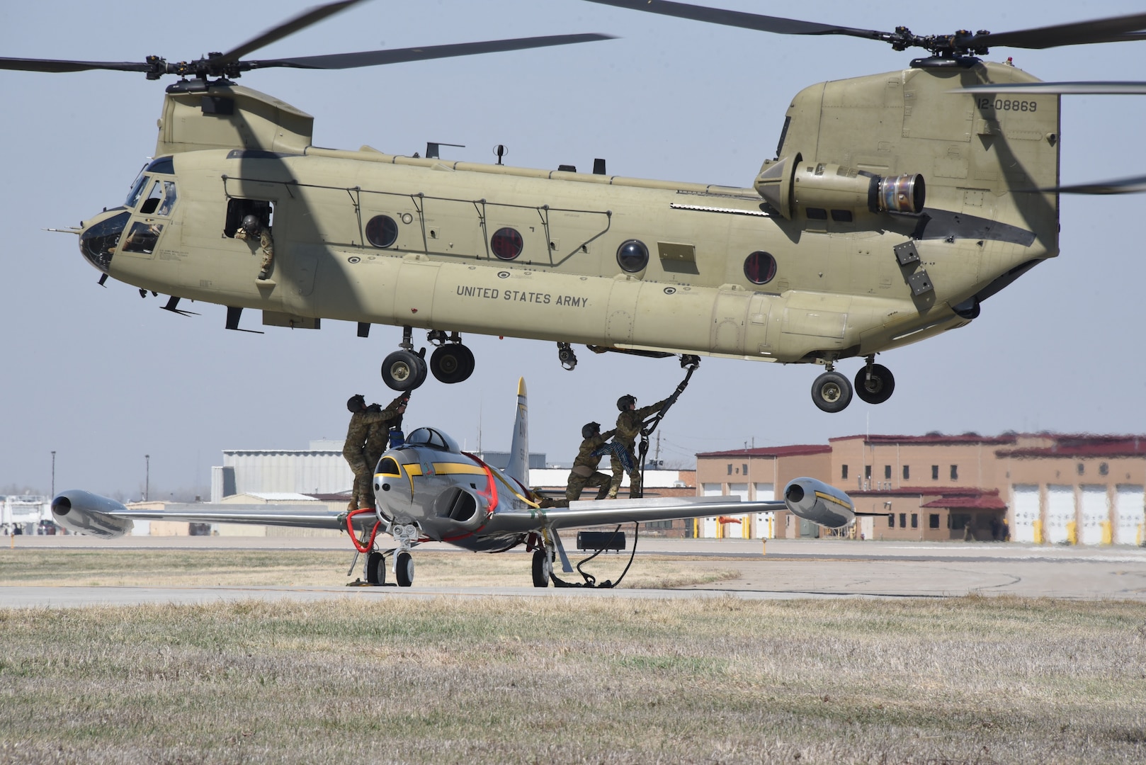An Iowa Army National Guard CH-47 Chinook helicopter picks up a historic F-80 fighter jet from the Air National Guard paint facility in Sioux City, Iowa, April 11, 2023. The helicopter from the Iowa National Guard B/171 Aviation Regiment based in Davenport brought the jet back to Camp Dodge to be placed on static display.