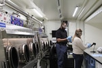 Lennox Brown and Shelby Bartram test the functionality of the equipment inside an Analytical Laboratory Systems Modified Work Order mobile laboratory at a DEVCOM CBC facility at Aberdeen Proving Ground, Maryland, before clearing the system for deployment.