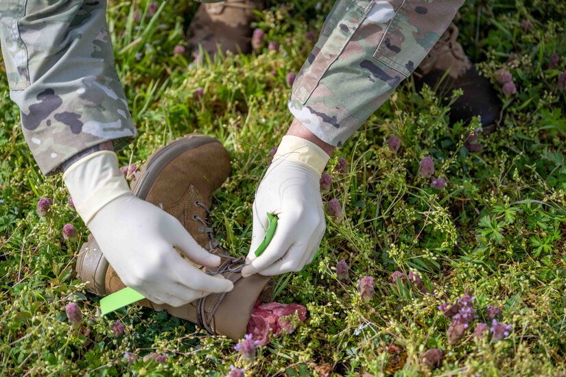 A boot with steak in it simulates the leg of a plane crash victim, while an Airman places a tag marking it on it.