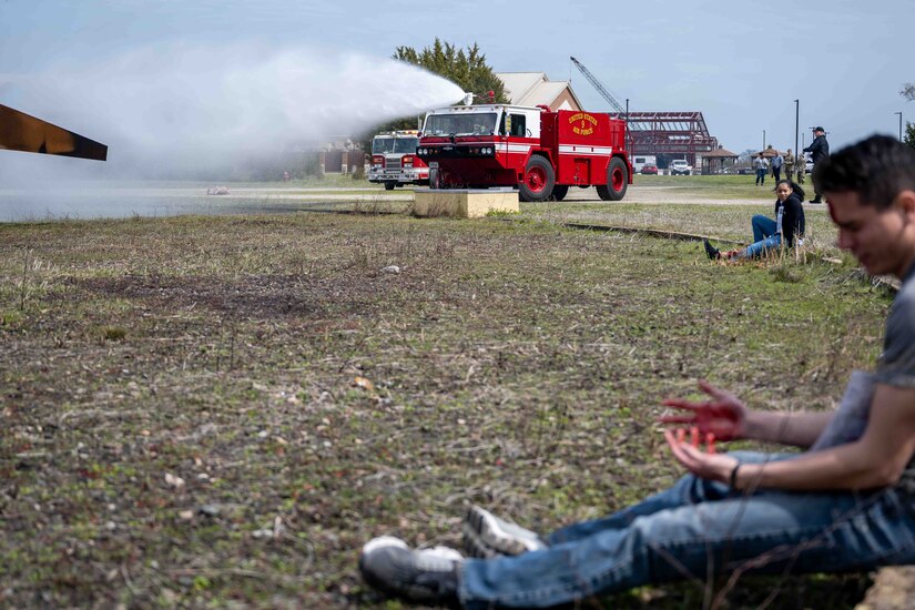 Firefighters suppress a fire in the background while simulated victims await aid in the foreground