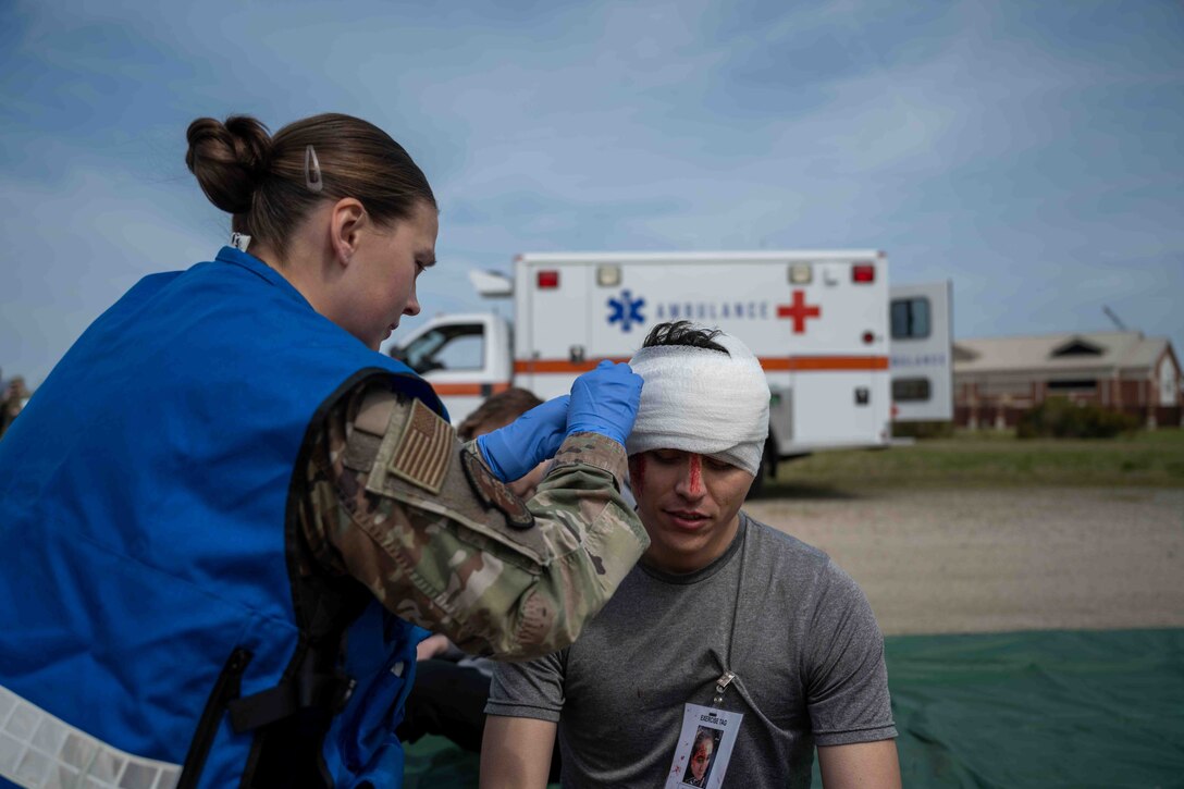 A U.S. Airman from the 633d Medical Group bandages the head of a simulated victim during an aircraft-mishap exercise