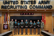 People stand in Army uniform on a stage.