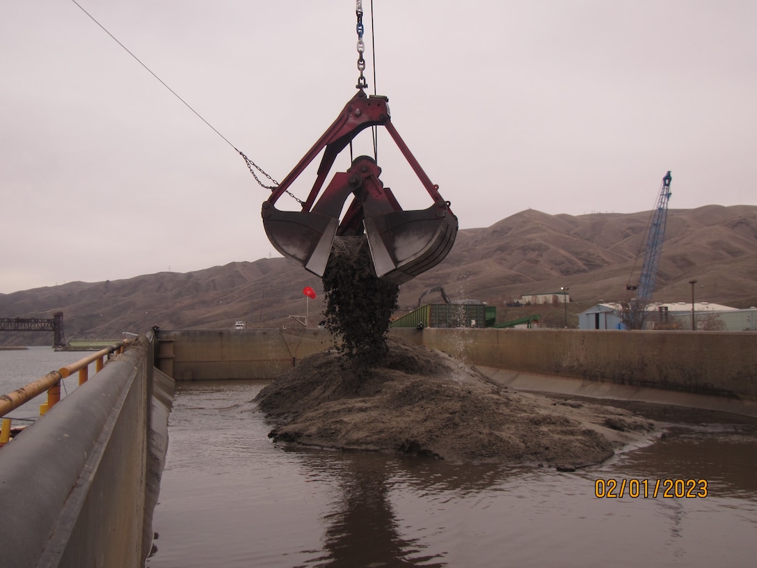 scoop dumping dredged material into the scow