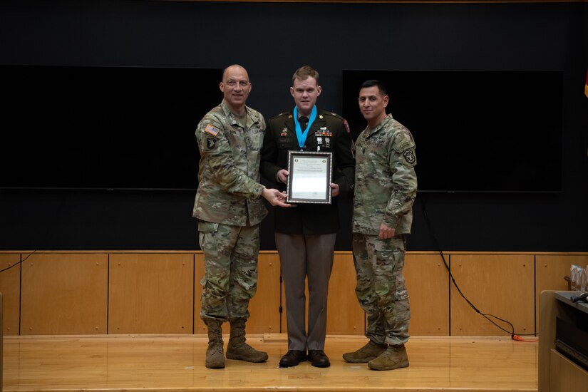 People stand in Army uniform on a stage.