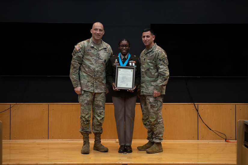 People stand in Army uniform on a stage.